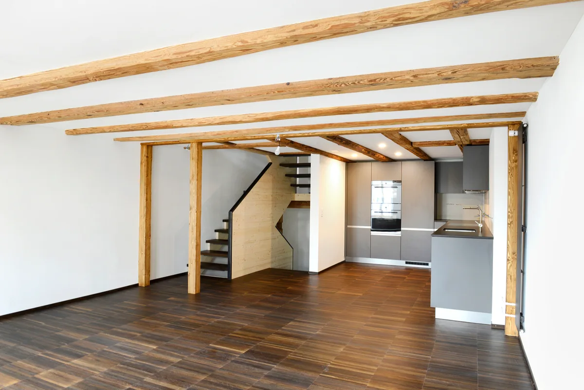 Ein renovierter Wohnbereich mit einer Küche und einer Treppe im Hintergrund.